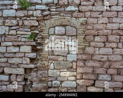 Alte Steinwand-Textur. Alte Backsteinmauer und Türbogen in Italien Stockfoto
