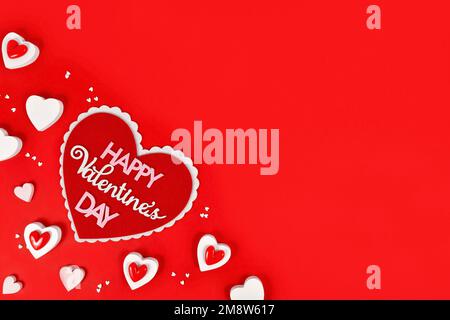 Valentinstag-Flachbett mit Herz, Text „Happy Valentine's Day“ und Herzschmuck auf rotem Hintergrund mit Kopierbereich Stockfoto