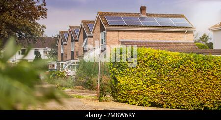 Eine Reihe von freistehenden Häusern aus der Mitte des Jahrhunderts mit Solarpaneelen auf dem Dach nahe Bristol, England, Großbritannien. Stockfoto