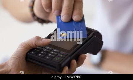 Männliche Hand hält Kreditkarte am POS-Terminal Stockfoto