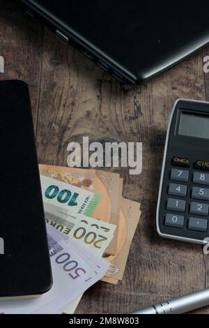 Buchfragment eines Kontogeräts mit Euro-Banknoten und einem Füllfederhalter auf einem Holztisch. Stockfoto