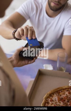 Männlicher Gast mit Kreditkarte im Café, bezahlt für das Essen Stockfoto