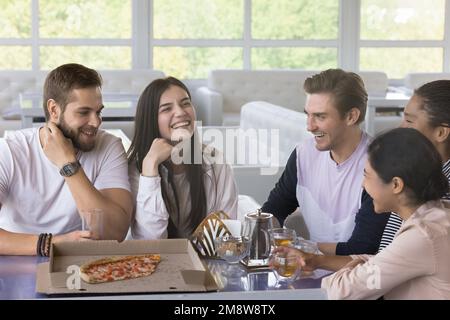 Fröhliche junge Freunde, die Spaß in der Pizzeria haben Stockfoto