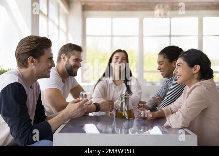 Ein vielseitiges junges Paar, das flirtet und lacht, weil es sich mit Freunden trifft Stockfoto