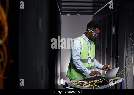 Grafik-Seitenansicht eines jungen Netzwerktechnikers, der Server im Rechenzentrum repariert, Kopierbereich Stockfoto