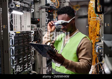 Porträt eines Technikers, der Server im Rechenzentrum repariert und Computerteile untersucht Stockfoto