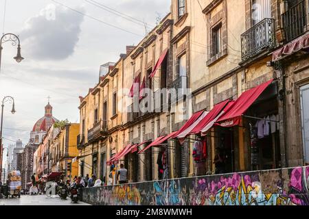 Eine mit Graffiti markierte Mauer entlang der Alhondiga-Straße mit der Kuppel der Kirche Templo de Santa Inés im Stadtviertel Zona Centro von Mexiko-Stadt, Mexiko. Stockfoto