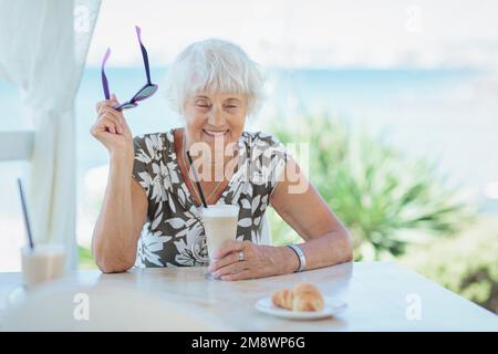 Wunderschöne ältere Frau mit einer Tasse Kaffee mit Milch Stockfoto