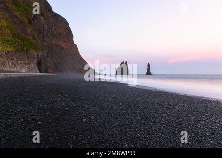 Das Meer stapelt sich an einem schwarzen Kieselstrand in Island unter Mitternachtssonne im Sommer Stockfoto