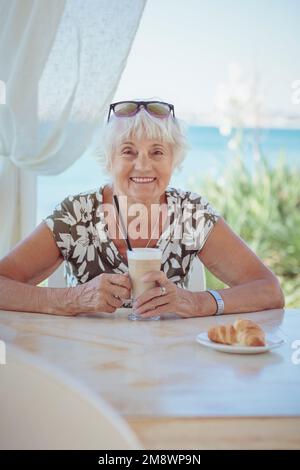 Wunderschöne ältere Frau mit einer Tasse Kaffee mit Milch Stockfoto