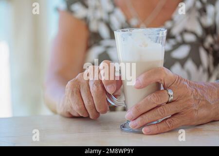 Zugeschnittenes Foto einer Seniorin, die draußen eine Tasse Kaffee hält Stockfoto