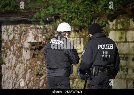 Erkelenz, Deutschland. 15. Januar 2023. Polizeikräfte stehen vor dem Gebäude, wo sich Aktivisten in einem Tunnel verbarrikadiert haben. Das Energieunternehmen RWE will die unter Lützerath liegende Kohle abbauen - zu diesem Zweck soll das Weiler auf dem Gebiet der Stadt Erkelenz im offenen Braunkohlebergwerk Garzweiler II abgerissen werden. Kredit: Thomas Banneyer/dpa/Alamy Live News Stockfoto