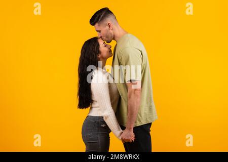 Fröhlicher, großer arabischer Ehemann, der seine Frau auf die Stirn küsst, ein Paar genießt Freizeit und einen zarten Moment Stockfoto