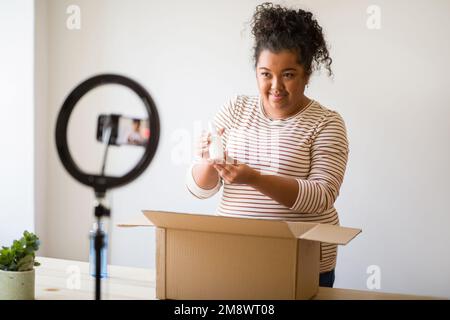 Süße, übergewichtige, junge Frau, Beauty-Bloggerin, die Gesichtspflegeprodukte zeigt Stockfoto