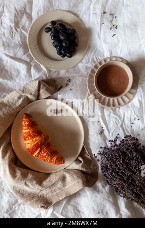 Traditionelles französisches Frühstück mit Croissant, Trauben und heißer Schokolade, Foto über Kopf Stockfoto
