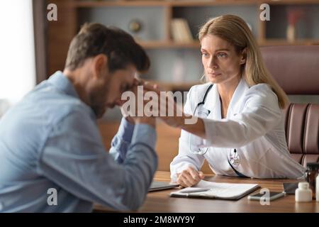 Arztfrau Tröstet Verärgerten Männlichen Patienten Während Des Meetings In Der Klinik Stockfoto