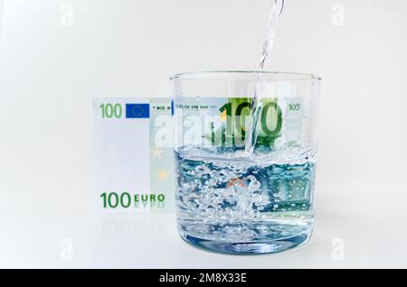 Wasser spritzt aus dem Glas mit Euro-Rechnung Hintergrund im Konzept des Wirtschaftswachstums Stockfoto