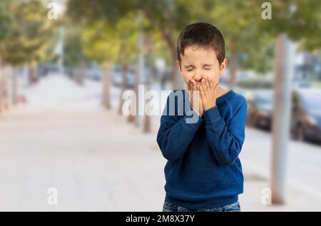 Kind, das an Husten als Symptom von Erkältung oder Bronchitis leidet, wenn es die Straße entlang geht Stockfoto