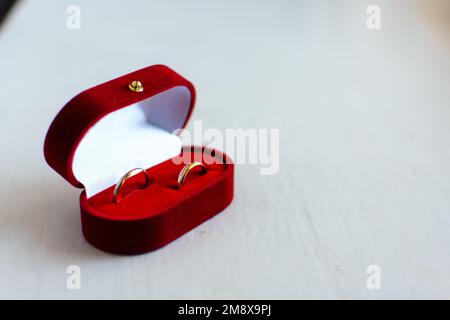 Ein Paar goldene Eheringe liegen in einer traditionellen roten Box Stockfoto