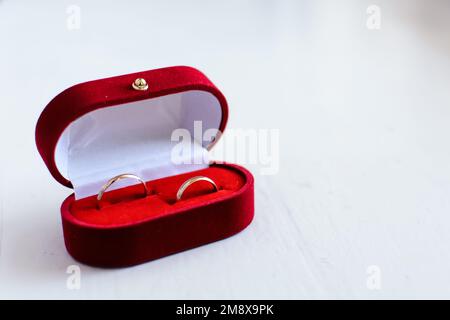 Ein Paar goldene Eheringe liegen in einer traditionellen roten Box Stockfoto