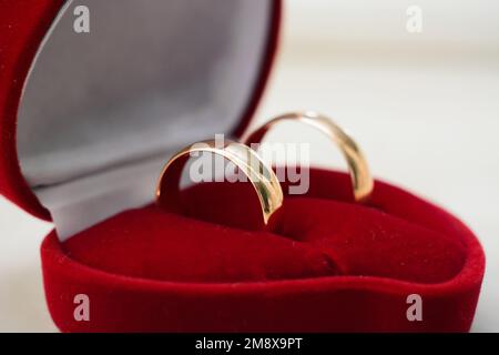 Ein Paar goldene Eheringe liegen in einer traditionellen roten Großaufnahme Stockfoto