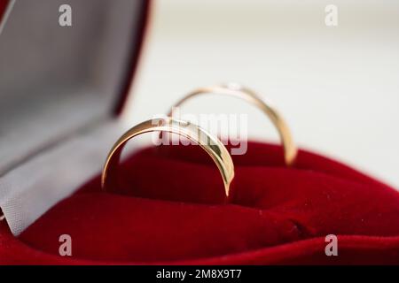 Ein Paar goldene Eheringe liegen in einer traditionellen roten Großaufnahme Stockfoto
