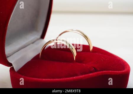 Ein Paar goldene Eheringe liegen in einer traditionellen roten Großaufnahme Stockfoto