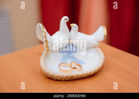 Zwei goldene Eheringe liegen auf einem Verlobungsplatte mit Tauben Stockfoto
