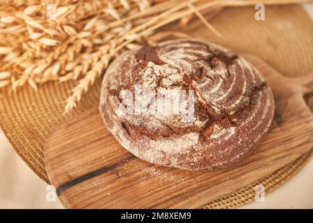 Vollkornbrot auf einem hölzernen Küchenteller. Frisches Brot auf dem Tisch, Nahaufnahme. Frisches Brot auf dem Küchentisch. Das Konzept der gesunden Ernährung und der traditionellen Bäckerei. Hochwertiges Foto Stockfoto