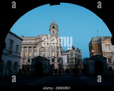 Anwesen entlang Whitehall, vom Eingangsbogen aus gesehen, in Horse Guards Parade mit den Wachhütten in Silhouette. London, England Stockfoto