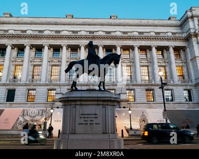 Reiterstatue in Silhouette auf Whitehall mit beleuchtetem Anwesen dahinter und vorbeifahrendem Verkehr. London, England Stockfoto