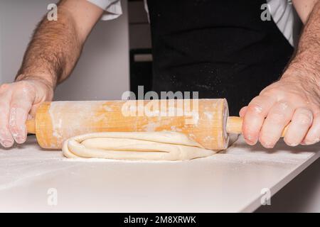 Der Konditor backt selbstgemachte Croissants, knettet Blätterteig mit Werkzeug, arbeitet zu Hause Stockfoto