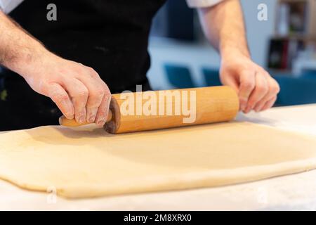 Der Konditor backt selbstgemachte Croissants, knettet Blätterteig mit Werkzeug, arbeitet zu Hause Stockfoto