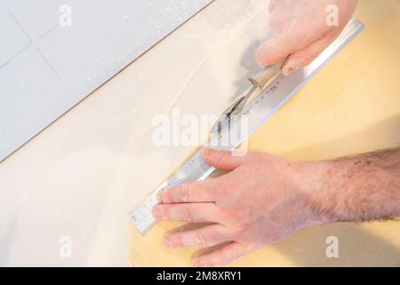 Der Konditor backt selbstgemachte Croissants, misst Blätterteig und schneidet, arbeitet zu Hause Stockfoto