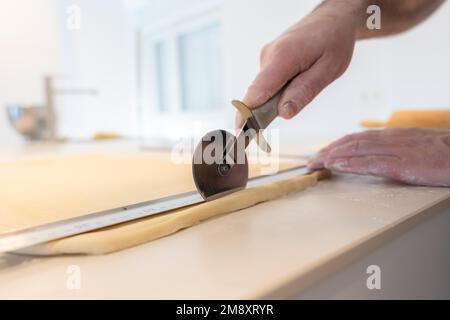 Der Konditor backt selbstgemachte Croissants, misst Blätterteig und schneidet, arbeitet zu Hause Stockfoto