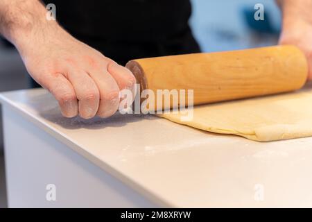 Der Konditor backt selbstgemachte Croissants, knettet Blätterteig mit Werkzeug, arbeitet zu Hause Stockfoto