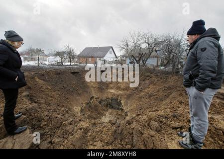 Nicht exklusiv: KOPYLIV, UKRAINE - 15. JANUAR 2023 - Ein Mann und eine Frau schauen sich einen Krater einer russischen Rakete an, Kopyliv, Kiew-Region, Nordukraine. Stockfoto