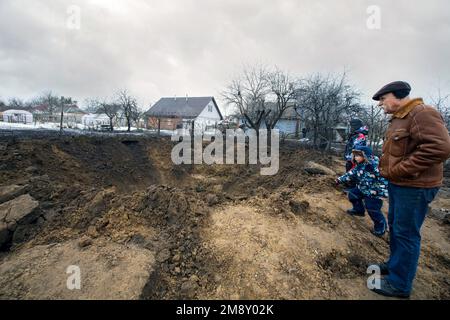 Nicht exklusiv: KOPYLIV, UKRAINE - 15. JANUAR 2023 - Ein Senioren und zwei Jungen stehen neben einem Krater einer russischen Rakete, Kopyliv, Kiew Region, Norden Stockfoto