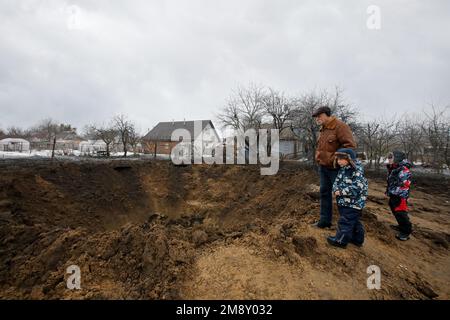 Nicht exklusiv: KOPYLIV, UKRAINE - 15. JANUAR 2023 - Ein Senioren und zwei Jungen stehen neben einem Krater einer russischen Rakete, Kopyliv, Kiew Region, Norden Stockfoto