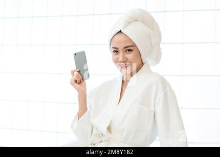 Eine junge Frau, die einen Bademantel für Handys trägt Stockfoto