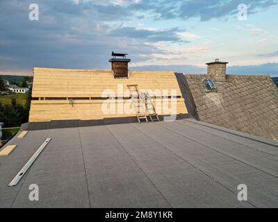 Installation neuer Dachplatten beim Bau des montierten Daches auf dem Haus Stockfoto