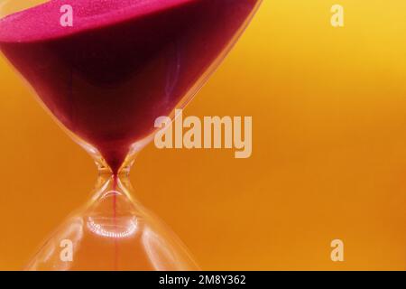 Makrofoto, Sanduhr aus Glas, auf hellem gelbem Hintergrund. Stockfoto