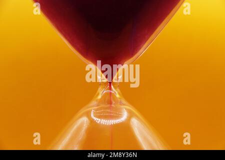 Makrofoto, Sanduhr aus Glas auf hellem gelbem Hintergrund. Stockfoto