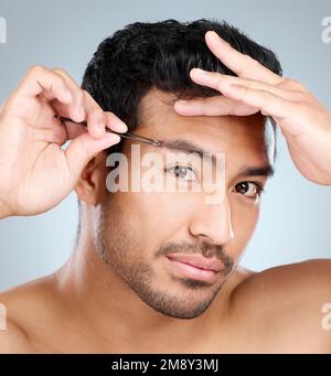 Ich fühlte mich sehr unsicher wegen meiner buschigen Augenbrauen. Ein gutaussehender Mann, der sich die Augenbrauen tanzt. Stockfoto