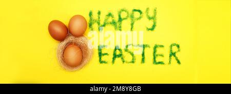 Inschrift Happy easter aus Gras mit Haseneiern und Nest auf gelbem Hintergrund. Platz für Text kopieren Stockfoto