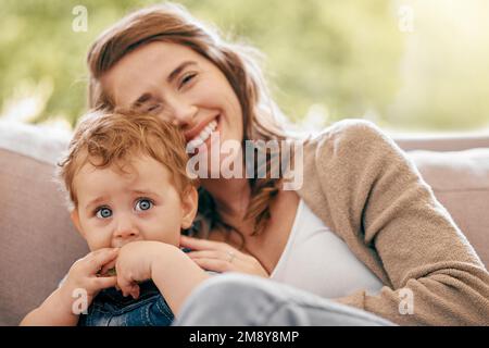 Sohn, du wirst über meinen Schoß wachsen, aber nie über mein Herz. Eine junge Mutter, die sich mit ihrem kleinen Jungen auf dem Sofa zu Hause anfreundet. Stockfoto