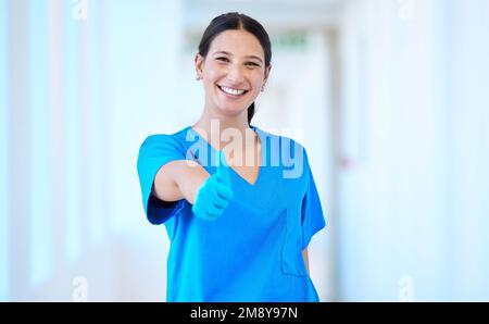 Sie verbreitet überall positive Gefühle. Eine junge, schöne Zahnarzthelferin, die die Daumen nach oben gibt. Stockfoto