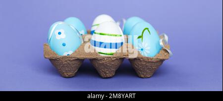 ostern bunte, handgefertigte blaue Eier in einer Schachtel auf perple, sehr peri Hintergrund. Banner Stockfoto