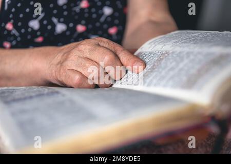 Eine alte Frau liest die Bibel, die Hände sind dicht. Stockfoto