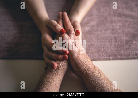 Ein alter und junger Mann, der Händchen hält, aus der Nähe. Stockfoto